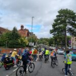 Photo of many children and adults cycling along the road in Guildford. There is a mass of cyclists going up the hill as far as the eye can see.